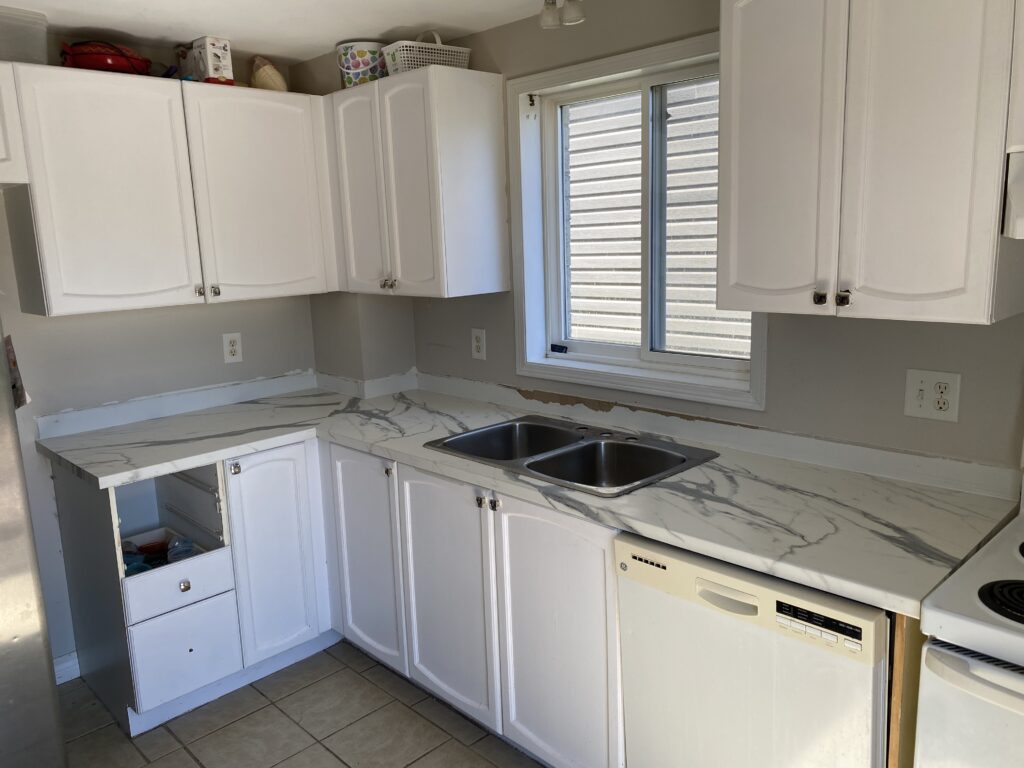 Modern white kitchen with marble countertops and stainless steel appliances.