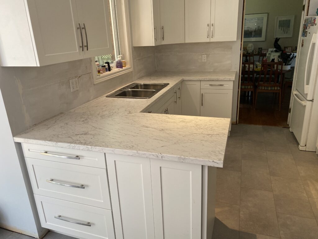 Modern kitchen with white marble countertop and cabinetry.