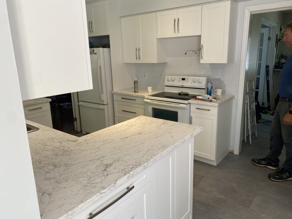 Modern kitchen with white cabinets and marble countertops.