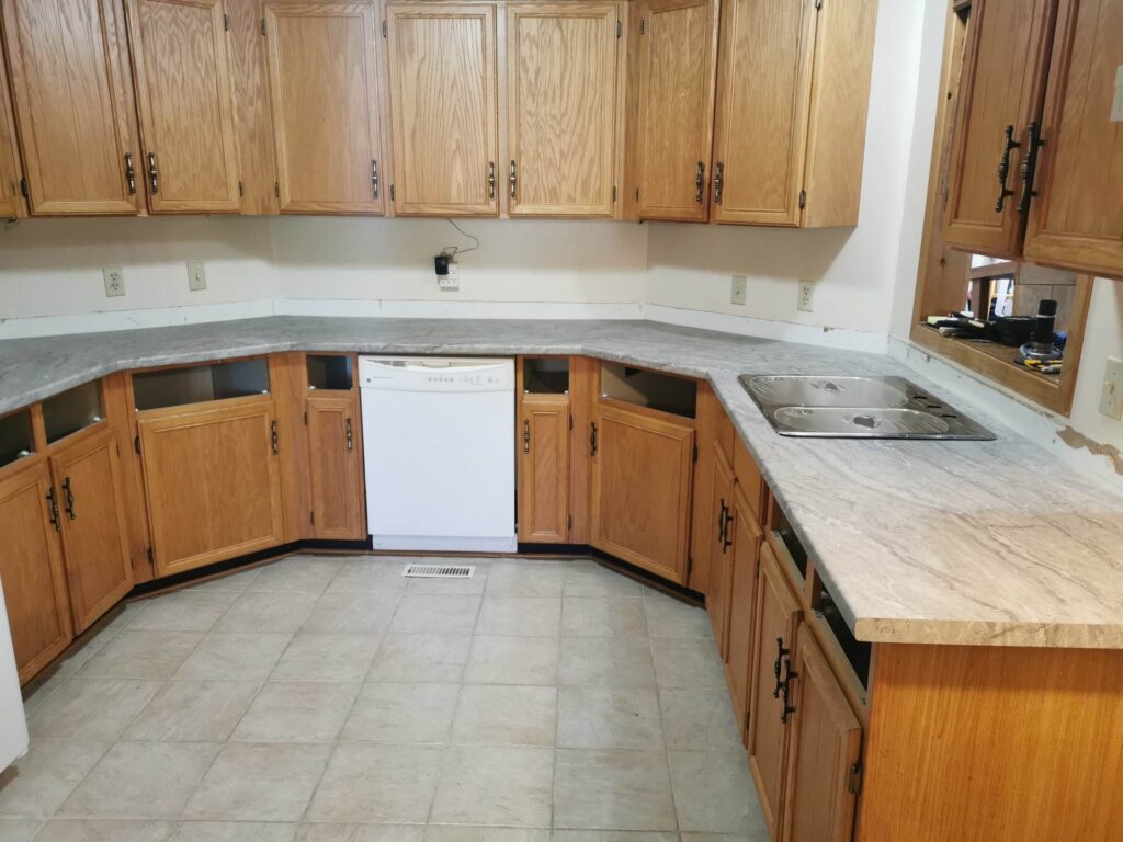 Kitchen with wooden cabinets, beige countertops, and tiled floor.